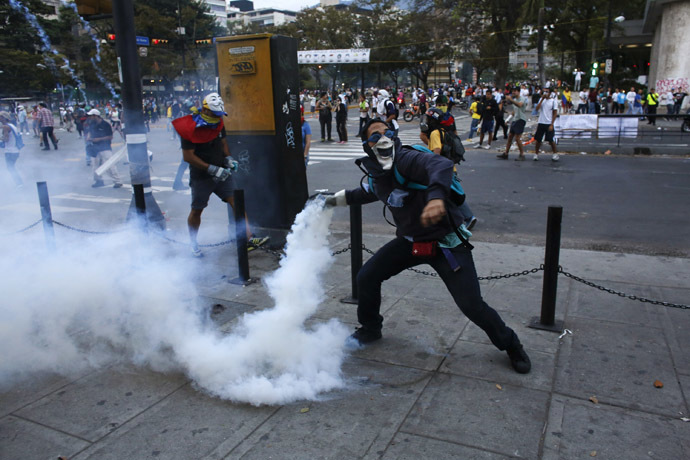 An anti-government demonstrator throws a teargas canister after it was thrown at protesters by the police, during clashes at Altamira square in Caracas February 27, 2014. (Reuters/Tomas Bravo)