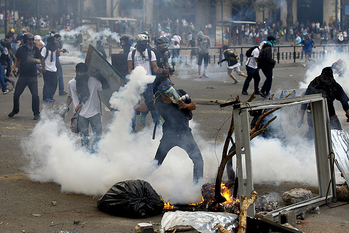 An anti-government protester throws a gas canister back at police during riots at Altamira square in Caracas March 6, 2014. (Reuters/Carlos Garcia Rawlins)