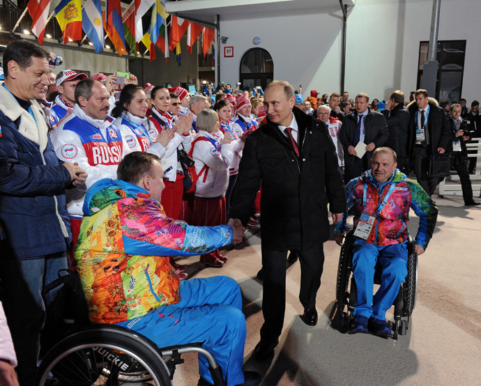 Russian President Vladimir Putin (C) shakes hands with poses with sportsmen as he visits the mountain Paralympic village outside Sochi on March 6, 2014 (AFP Photo)