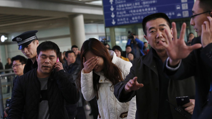 A relative (C, in white) of a passenger onboard Malaysia Airlines flight MH370, covers her face as she cries at the Beijing Capital International Airport in Beijing March 8, 2014.(Reuters / Kim Kyung-Hoon)