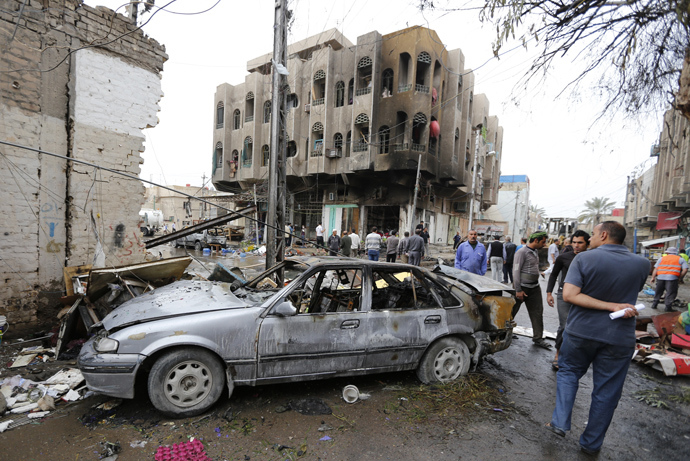 People look at the site of a car bomb attack in the neighbourhood of al-Qahera in northern Baghdad, March 9, 2014 (Reuters / Thaier al-Sudani)