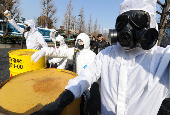 People wearing protective suits and masks shout slogans next to mock drums (L) of nuclear waste from the Fukushima Daiichi nuclear power plant, during a march denouncing nuclear power plants in Tokyo on March 9, 2014. (AFP Photo / Toru Yamanaka)