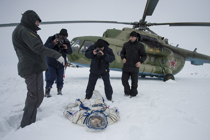 A photographer and an operator document the suit worn byAstronaut Michael Hopkins from NASA after the landing of the Soyuz TMA-10M capsule in a remote area southeast of the town of Zhezkazgan in central Kazakhstan, March 11, 2014. (Reuters / Bill Ingalls / NASA / Handout via Reuters) 