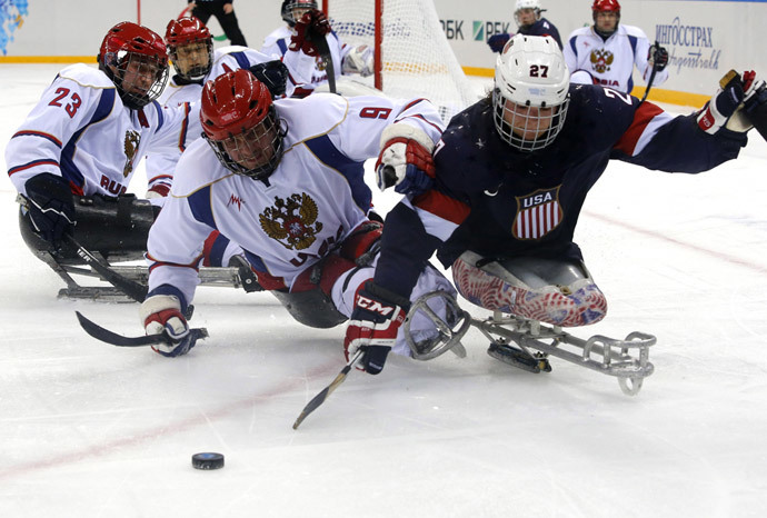Joshua Pauls of the U.S. (R) fights for the puck with Russia's Konstantin Shikhov (C) and Ilia Volkov during their ice sledge hockey game at the 2014 Sochi Paralympic Winter Games, March 11, 2014. (Reuters / Alexander Demianchuk)