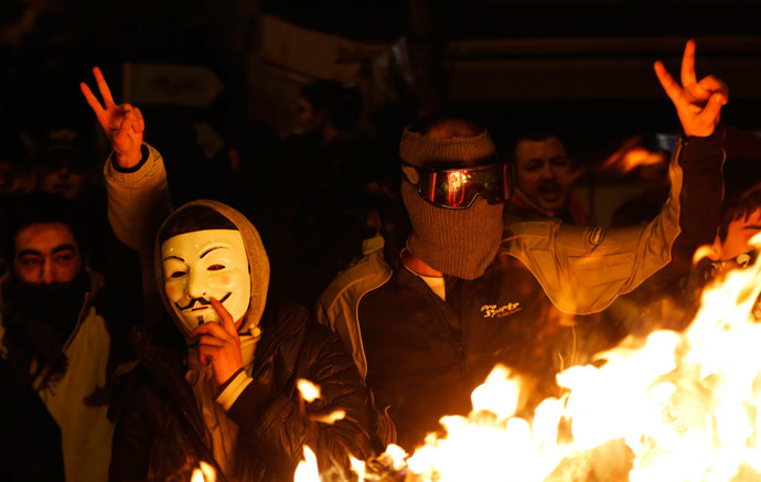 An anti-government protester wearing a Guy Fawkes mask stands with others behind a barricade that they set on fire during a demonstration in Ankara March 12, 2014. (Reuters / Umit Bektas)