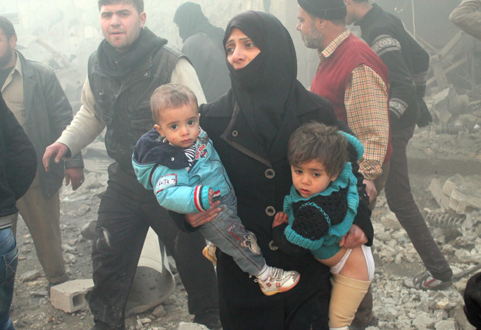 A file photo taken on December 15, 2013 shows a Syrian woman carrying children following airstrikes in northern city of Aleppo. (AFP Photo / Mohammed Al-Khatieb) 