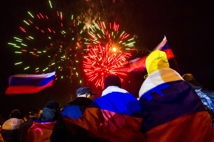 People wrapped with Russian flags watch fireworks during celebrations after the preliminary results of today's referendum are announced on Lenin Square in the Crimean capital of Simferopol March 16, 2014 (Reuters / Thomas Peter)