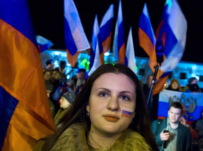 A woman with her face painted in the colours of the Russian national flag waits for the announcement of preliminary results of today's referendum on Lenin Square in the Crimean capital of Simferopol March 16, 2014 (Reuters / Thomas Peter)