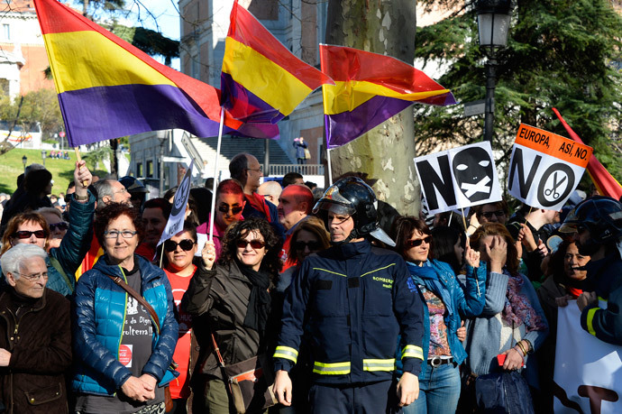 A fireman stands in front of demonstrators, some of them waving flags of the Spanish second republic, during a march dubbed "the Marches for Dignity 22-M" to protest against austerity in Madrid on March 22, 2014. (AFP Photo / Gerard Julien)