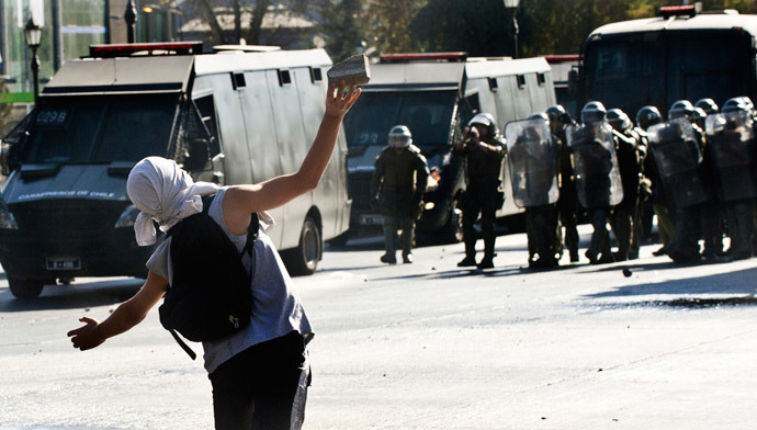 A demonstrator throws stones to riot policemen during a protest to demand free and good quality education and a call for a Constituent Assembly, in Santiago, on March 22, 2014. (AFP Photo / Martin Bernetti)