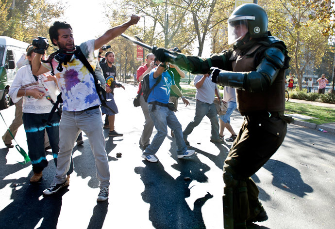 A demonstrator confronts a riot policeman during a protest to demand free and good quality education and a call for a Constituent Assembly, in Santiago, on March 22, 2014. (AFP Photo / Martin Bernetti)