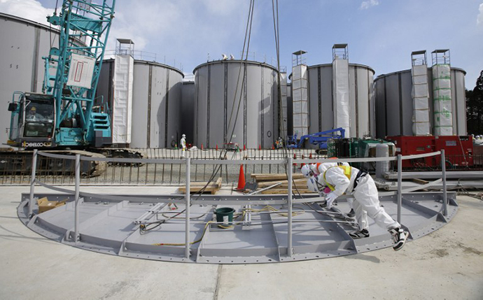 Men wearing protective suits and masks work in front of welding storage tanks for radioactive water, under construction in the J1 area at the Tokyo Electric Power Co's (TEPCO) tsunami-crippled Fukushima Daiichi nuclear power plant in Okuma in Fukushima prefecture (AFP Photo / Toru Hanai)