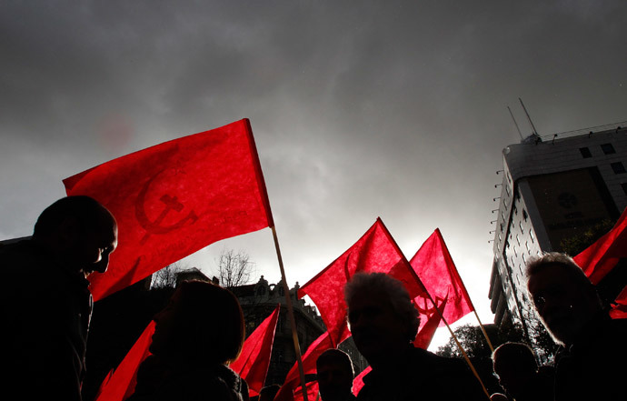 Demonstrators hold flags of the Communist Party during an anti-NATO march in downtown Lisbon (Reuters / Juan Medina)