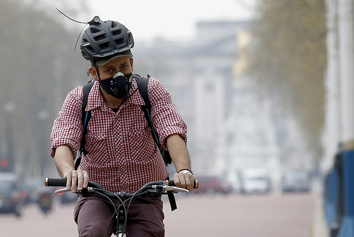A cyclist wears a mask as he cycles near Buckingham Palace in London April 2, 2014. (Reuters / Luke MacGregor)