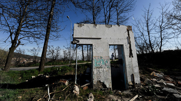 A Kosovo Albanian woman walks on March 22, 2014 past former Yugoslav army barracks, near the town of Mitrovica, which were destroyed during the 1999 NATO air campaign against Serbia.(AFP Photo / Armend Nimani)