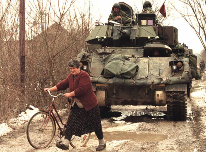 A Bosnian Serb woman makes her way between vehicles of a US troop convoy of the NATO peace enforcement forcce (IFOR) on a dirt road near Pelagicevo in a Serb-held area of the northern Bosnian Posavina corridor 02 January 1996.(AFP Photo / Pascal Guyot)