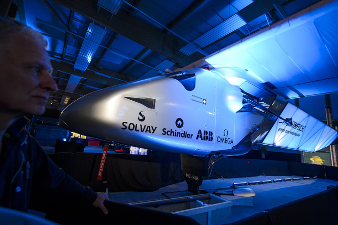 A staff of Solar Impulse stands next to the second solar-powered plane, the HB-SIB, which Swiss pilots Bertrand Piccard and Andre Borschberg aim to take on a round-the-world voyage next year, during is unveiling on April 9, 2014 in Payerne (AFP Photo / Fabrice Coffrini)