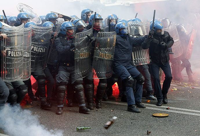 Policemen take shelter from bottles and flares thrown by demonstrators during a protest in downtown Rome April 12, 2014. (Reuters / Alessandro Bianchi)