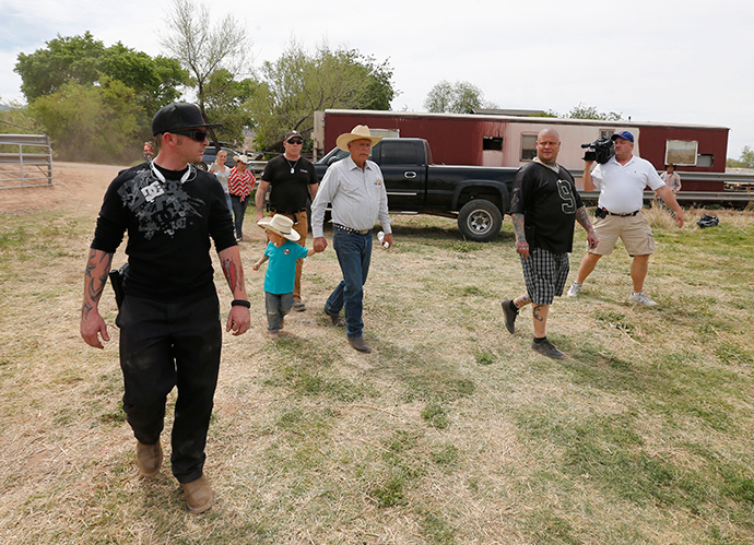Rancher Cliven Bundy (C), with his grandson Braxton Louge in tow and armed security guards leave his ranch house on April 11, 2014 west of Mesquite, Nevada (AFP Photo / George Frey)