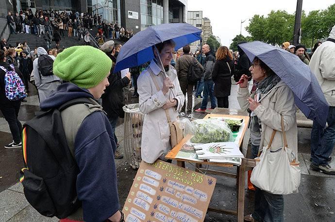 A woman (C) sells bags and caps on which are drawn cannabis leafs while people take part in a protest to call for the legalization of marijuana on May 10, 2014 in Paris. (AFP Photo / Pierre Andrieu)