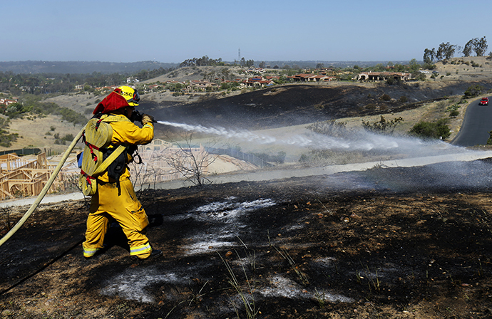 A fire-fighter works to put out spot fires caused by strong winds as they keep close watch over the Bernardo fire north of San Diego, California May 14, 2014. (Reuters / Mike Blake)