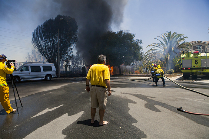 Greg Saska watches his mother's house burn as firefighters battle a fire in Carlsbad, California May 14, 2014. (Reuters / Sam Hodgson)