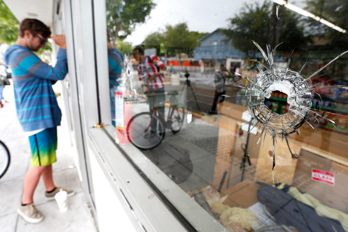 A man looks through a window with bullet holes at a deli that was one of nine crime scenes after series of drive -by shootings that left 7 people dead in the Isla Vista section of Santa Barbara May 24, 2014. (Reuters / Jonathan Alcorn)