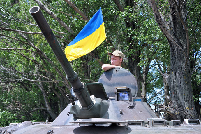 A Ukrainian soldier stands guard next to an Armoured Personnel Carriers (APC) as a flag of Ukraine floats in the background, on the road from Izyum to Slavyansk on May 20, 2014. (AFP Photo)