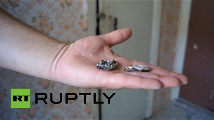 A woman working at Slavyansk school no.13 shows shrapnel of the shell that hit the school's roof on May 28, 2014. (A screenshot from Ruptly video)