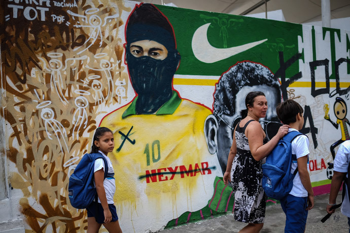 People walk past a vandalized graffiti depicting Brazilian national footballer Neymar with a hood used by members of the anarchist group known as Black Bloc which is against of the FIFA World Cup Brazil 2014 football tournament, in Rio de Janeiro, Brazil, on May 27, 2014. (AFP Photo / Yasuyoshi Chiba) 