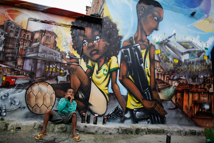 Ryan, 9, eats in front of graffiti painted by members of OPNI, in reference to the 2014 World Cup, in the Vila Flavia slum of Sao Paulo May 28, 2014. (Reuters / Nacho Doce) 