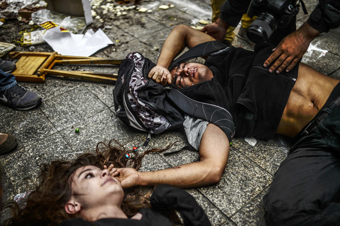  Injured protesters lie on the ground as Turkish riot police officers fire tear gas to disperse demonstrators gathered on the central Istoklal avenue near Taksim square in Istanbul, on May 31, 2014, as the police blocked access to the square during the one year anniversary of the Gezi park and Taksim square demonstrations. (AFP Photo/Bulent Kilic)