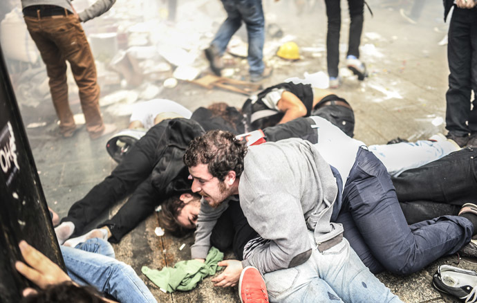Injured protesters lie on the ground as Turkish riot police officers fire tear gas to disperse demonstrators gathered on the central Istoklal avenue near Taksim square in Istanbul, on May 31, 2014, as the police blocked access to the square during the one year anniversary of the Gezi park and Taksim square demonstrations. (AFP Photo/Bulent Kilic)