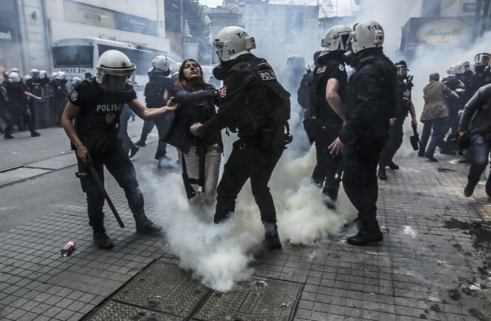 Turkish riot police officers hold up a protester seriously affected by tear gas as police officers use tear gas to disperse protesters who gathered on the central Istoklal avenue near Taksim square in Istanbul, on May 31, 2014, as the police blocked access to the square during the one year anniversary of the Gezi park and Taksim square demonstrations (AFP Photo/GURCAN OZTURK)
