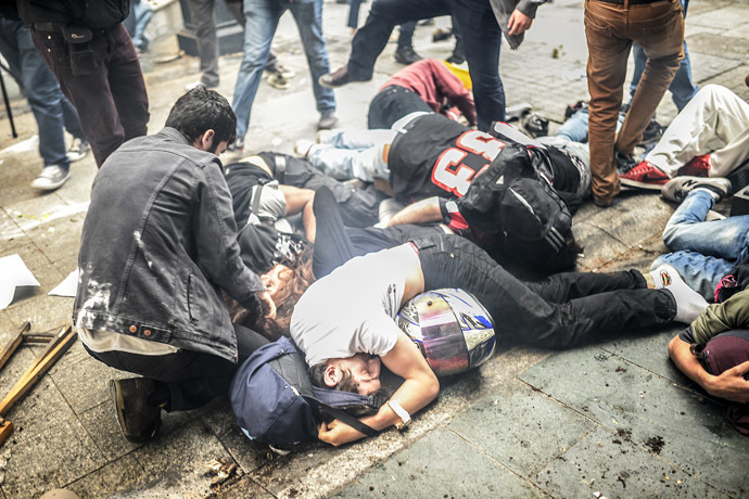 Injured protesters lie on the ground as Turkish riot police officers fire tear gas to disperse demonstrators gathered on the central Istoklal avenue near Taksim square in Istanbul, on May 31, 2014, as the police blocked access to the square during the one year anniversary of the Gezi park and Taksim square demonstrations. (AFP Photo/Bulent Kilic)