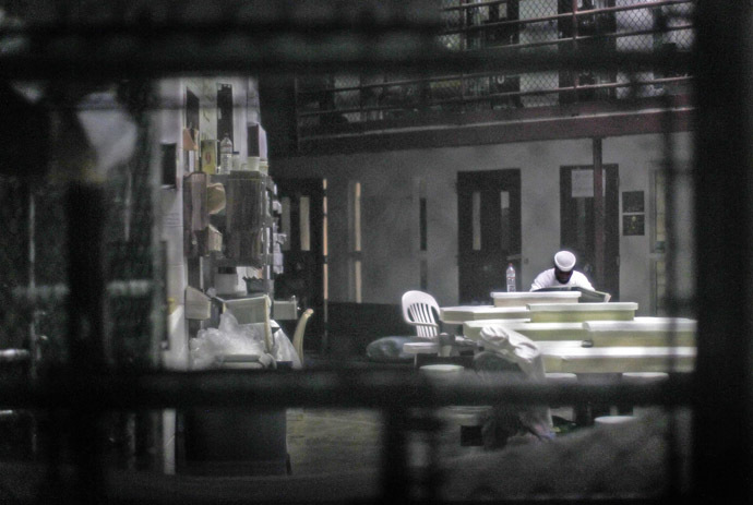 An unidentified prisoner reads a newspaper in a communal cellblock at Camp VI, a prison used to house detainees at Guantanamo Bay U.S. Naval Base, March 5, 2013. (Reuters/Bob Strong)