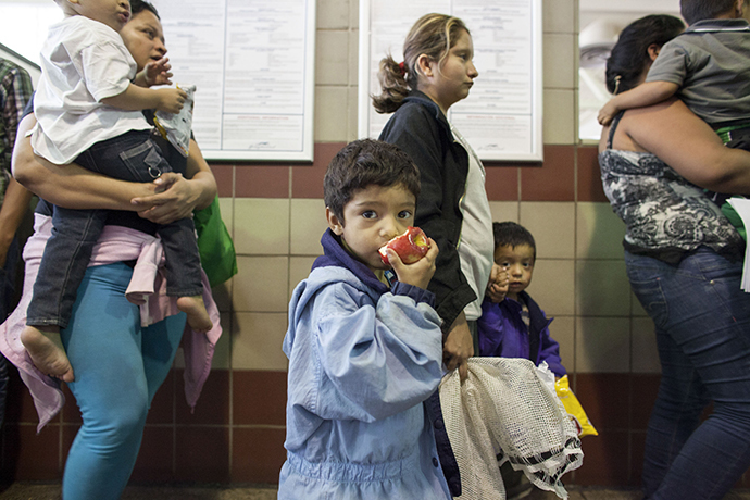 Migrants, consisting of mostly women and children, who just disembarked from a U.S. Immigration and Customs Enforcement (ICE) bus wait for a Greyhound official to process their tickets to their next destination at a Greyhound bus station in Phoenix, Arizona May 29, 2014. (Reuters / Samantha Sais)