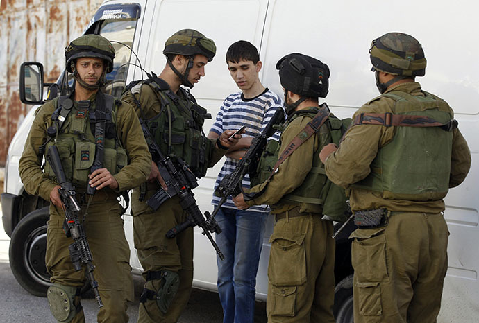 Israeli soldiers search a Palestinian youth during an operation to locate three Israeli teens in the West Bank city of Hebron June 16, 2014. (Reuters / Ammar Awad)