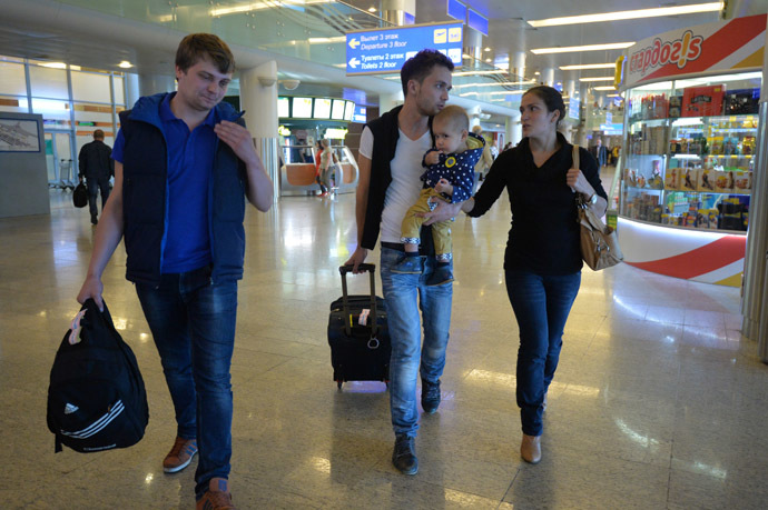 Zvezda TV channel correspondent Evgeny Davydov, center, with his family and sound engineer Nikita Konashenkov on their arrival at Moscow's Sheremetyevo airport. (RIA Novosti/Alexey Kudenko)