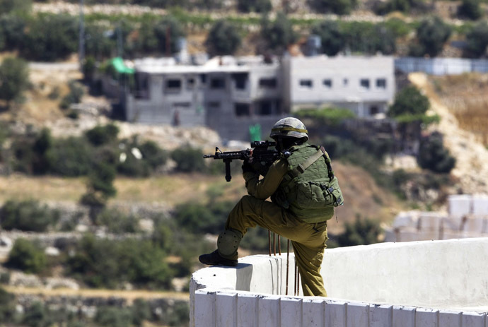 An Israeli soldier takes position during an operation to locate three missing teenagers, in the West Bank city of Hebron June 18, 2014. (Reuters/Ronen Zvulun)