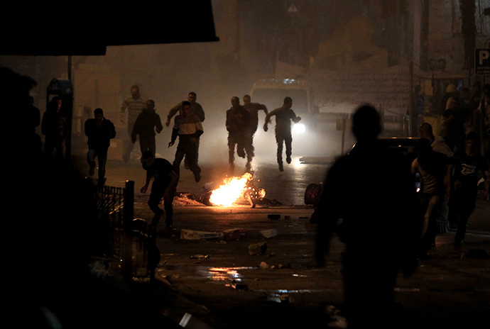 Palestinians run for cover during clashes with Israeli security forces taking part in the search for three missing teenagers early on June 22, 2014 in the West Bank city of Ramallah (AFP Photo / Abbas Momani)
