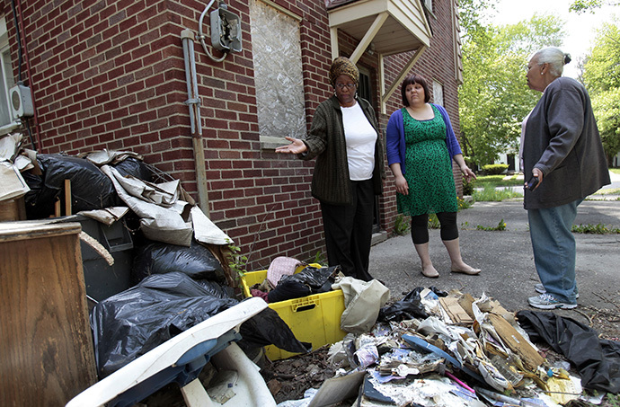 volunteers with Grandmont Rosedale's Vacant Property Task Force take note of illegal debris behind a vacant house in the North Rosedale neighborhood of Detroit, Michigan. (Reuters / Rebecca Cook)