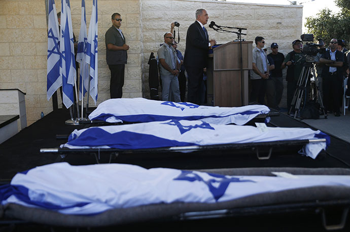 Israeli Prime Minister Benjamin Netanyahu (Background) delivers a speech next to the bodies of Gilad Shaer and Naftali Frenkel, both 16, and 19-year-old Eyal Ifrach, all three wrapped in their national flag, as he attends their funeral on July 1, 2014 in the cemetery of Modiin in central Israel. (AFP Photo / Baz Ratner)