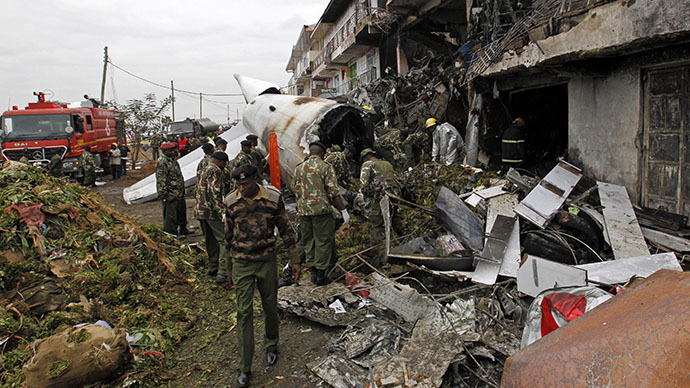Security personnel stand at the site of the wreckage of a cargo plane that crashed into a commercial building on the Utawala estate on the outskirts of Kenya's capital Nairobi, July 2, 2014. (Reuters / Thomas Mukoya)