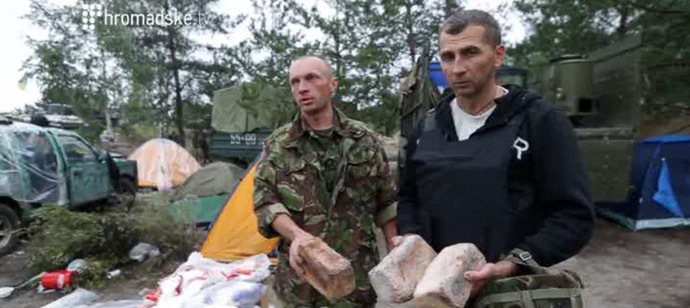 National Guard fighters showing mould-covered bread loaves. Still from Hromadske.tv video