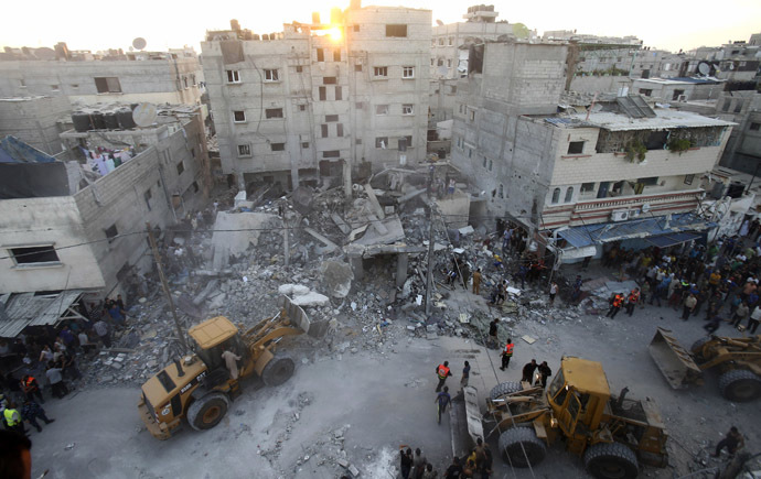 Bulldozers remove debris as Palestinians and rescue workers search for victims under the rubble of a house which police said was destroyed in an Israeli air strike in Rafah in the southern Gaza Strip July 11, 2014. (Reuters/Ibraheem Abu Mustafa)