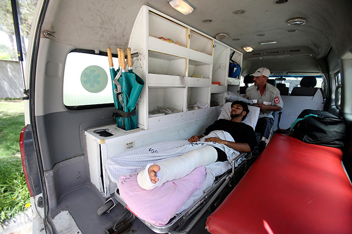 A Palestinian man, whom medics said was wounded in an Israeli air strike, lies on a bed inside an ambulance waiting to cross into Egypt, at the Rafah crossing on the southern Gaza Strip July 12, 2014. (Reuters / Ibraheem Abu Mustafa) 