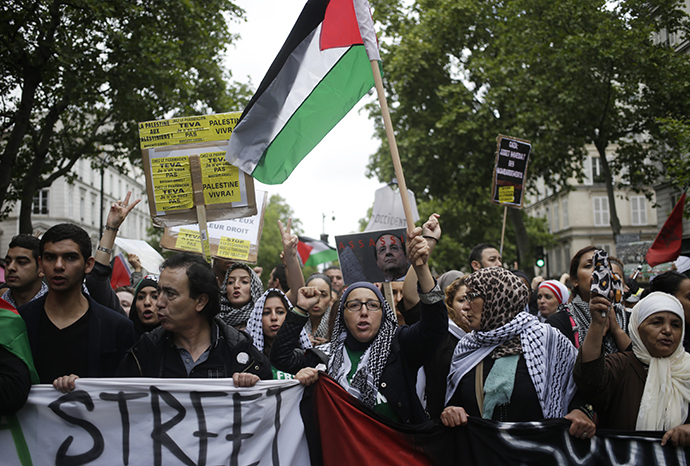 Protesters hold Palestinian flags banners and placards, including one with the image of French president Francois Hollande and the word "assassin", on July 13, 2014 in Paris. (AFP Photo / Kenzo Tribouillard)
