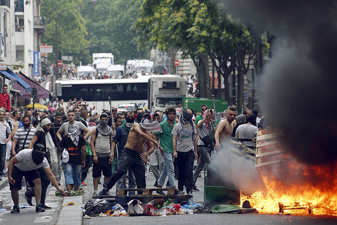 Protesters throw projectiles at French riot police behind a fire barricade near the aerial metro station of Barbes-Rochechouart, in Paris, on July 19, 2014, during clashes with French riot police in the aftermath of a demonstration, banned by French police, to denounce Israel's military campaign in Gaza and show support to the Palestinian people. (AFP Photo / Francois Guillot)