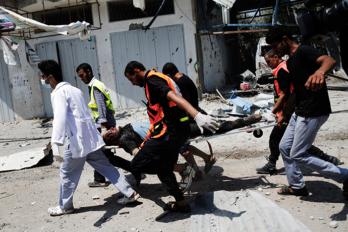 Medics carry a wounded Palestinian man through the Shejaia neighbourhood, which was heavily shelled by Israel during fighting, in Gaza City July 20, 2014 (Reuters / Finbarr O'Reilly)